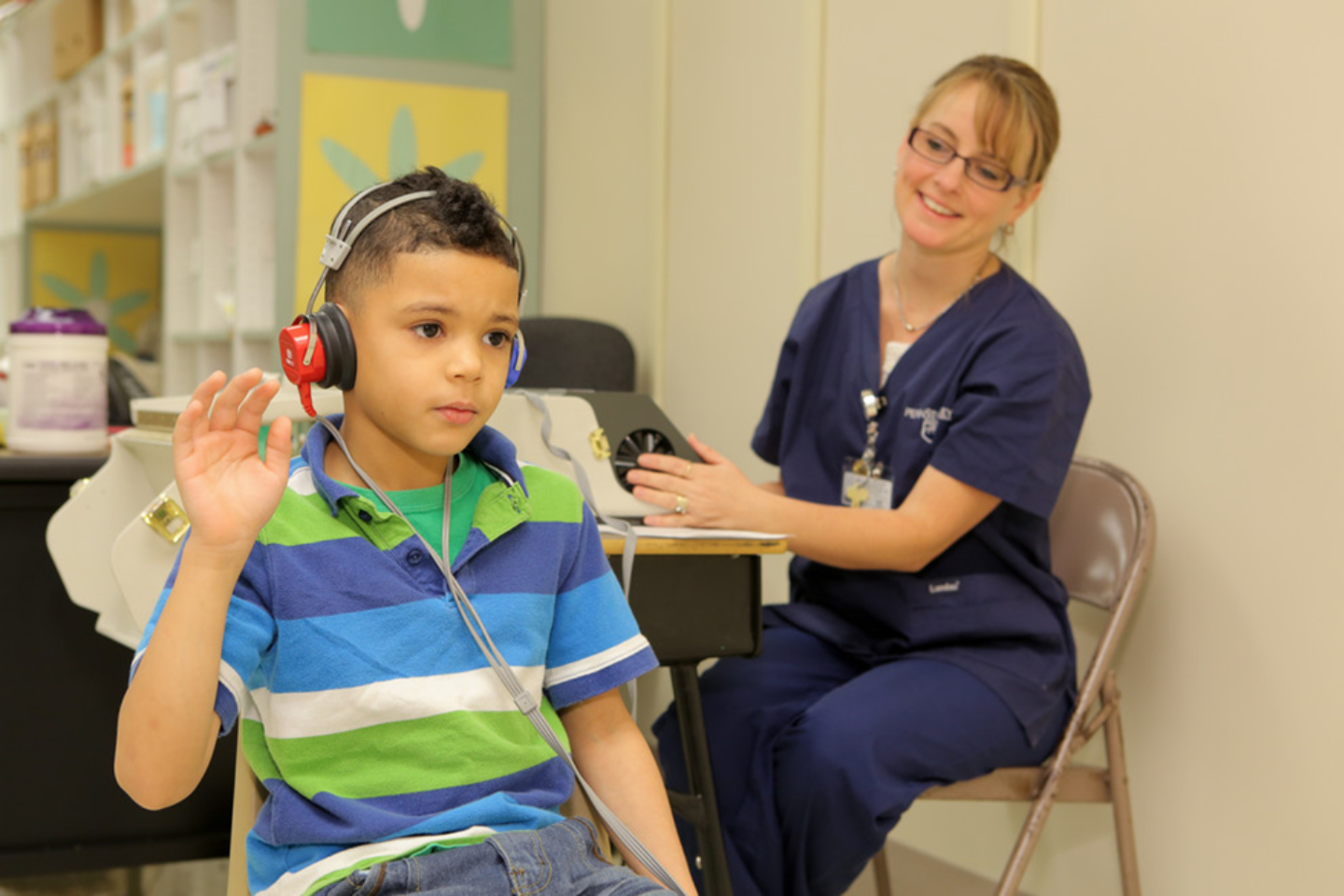 Audiologist testing young boy's hearing.